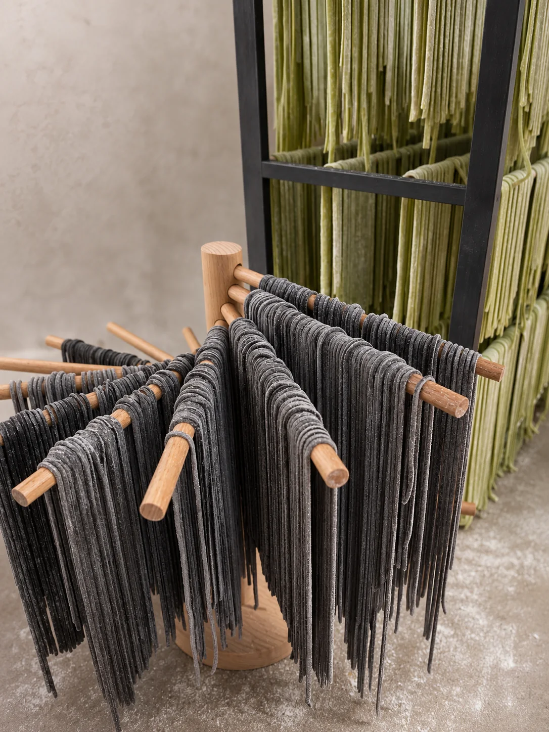 Handmade black and green pasta drying on wooden racks