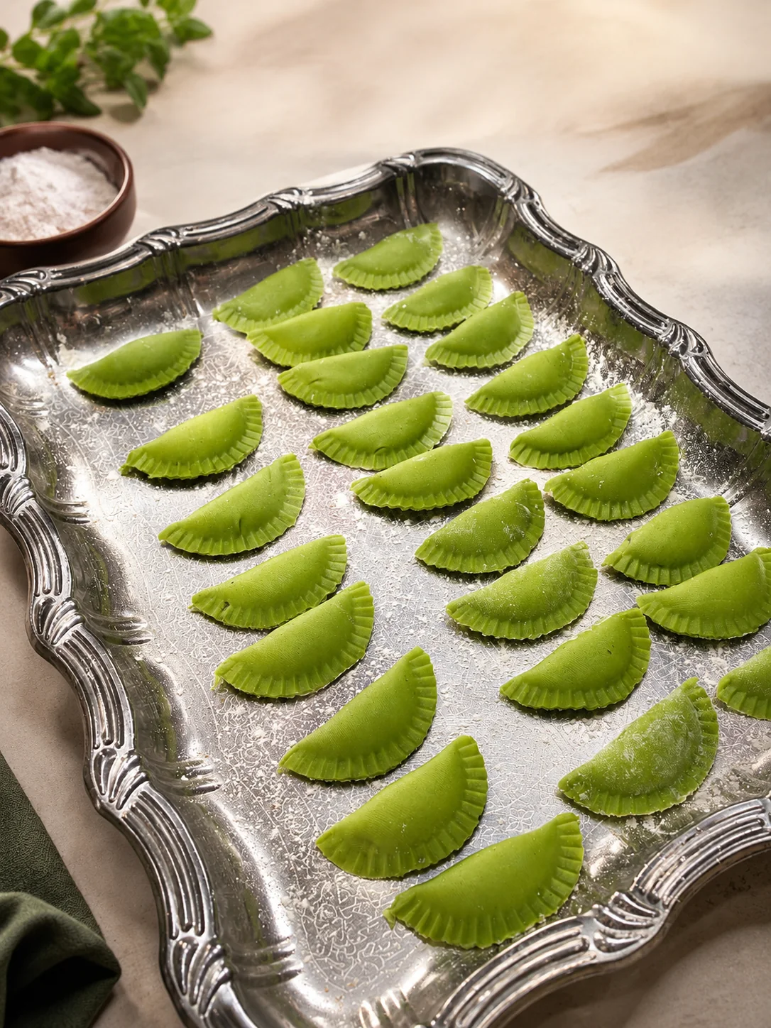 Green handmade filled pasta arranged on a silver tray